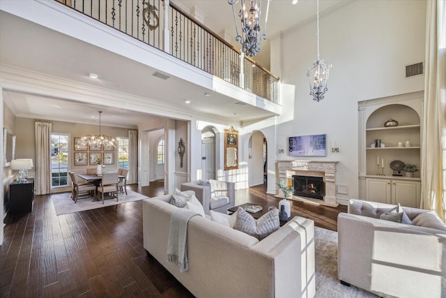 living area with an inviting chandelier, arched walkways, visible vents, and dark wood-type flooring