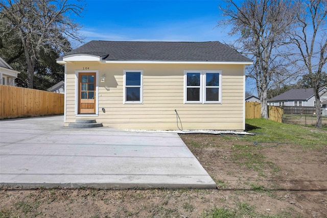 back of property with roof with shingles and fence