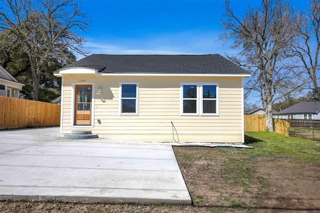 view of front of house with entry steps, a shingled roof, a front lawn, and fence