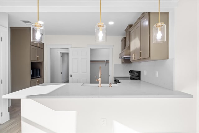 kitchen with a peninsula, light countertops, wall chimney range hood, black range with electric cooktop, and a sink