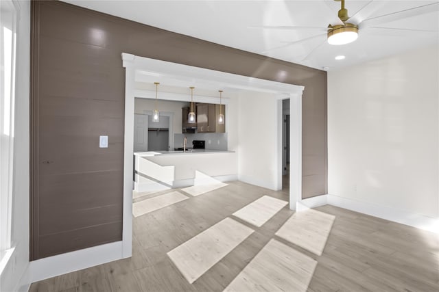 unfurnished living room with light wood-style floors, baseboards, and a sink