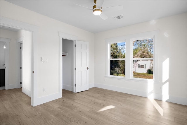 unfurnished bedroom featuring light wood-type flooring, baseboards, a spacious closet, and visible vents