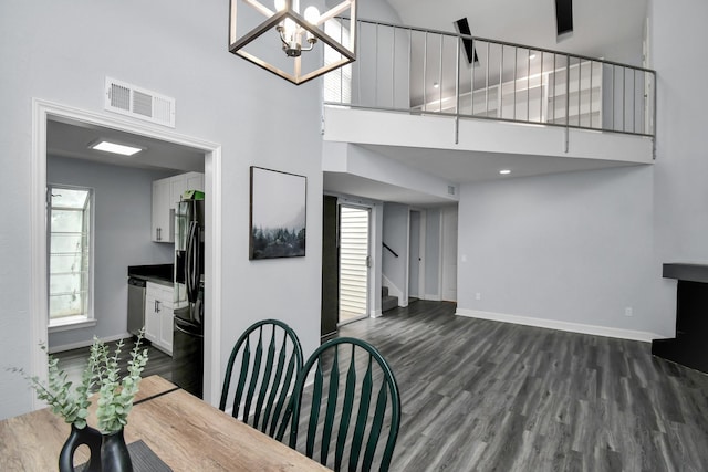 dining area with dark wood-style flooring, visible vents, a towering ceiling, and stairs