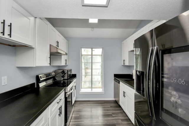 kitchen with stainless steel appliances, dark countertops, white cabinets, and under cabinet range hood