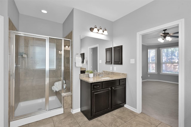 bathroom with ceiling fan, vanity, baseboards, a shower stall, and tile patterned floors