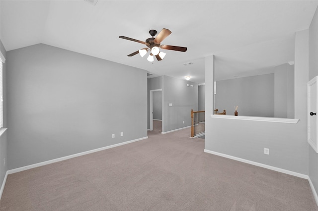 empty room with carpet floors, baseboards, vaulted ceiling, and a ceiling fan