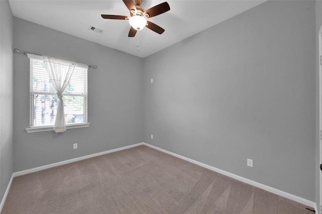 carpeted spare room featuring baseboards, visible vents, and ceiling fan