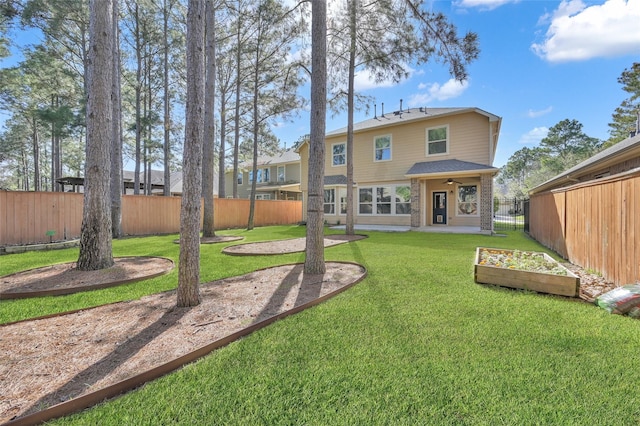 back of house with a yard, brick siding, and a fenced backyard