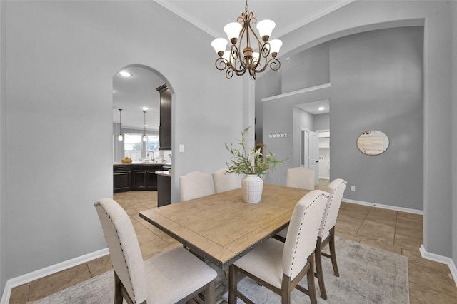 dining room featuring arched walkways, light tile patterned floors, a high ceiling, ornamental molding, and baseboards