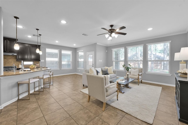 living area featuring baseboards, visible vents, crown molding, and light tile patterned flooring