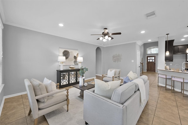 living area with light tile patterned floors, ceiling fan, visible vents, and arched walkways