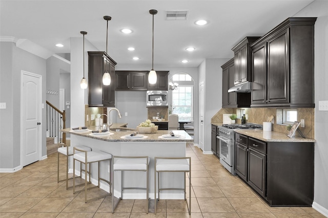 kitchen with a breakfast bar area, stainless steel appliances, a sink, visible vents, and light stone countertops