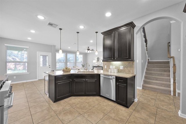 kitchen featuring arched walkways, stainless steel appliances, a sink, visible vents, and decorative backsplash