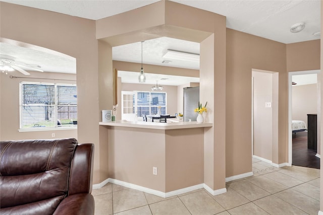 kitchen featuring light countertops, freestanding refrigerator, open floor plan, light tile patterned flooring, and baseboards