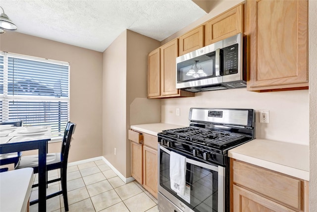 kitchen with light brown cabinets, appliances with stainless steel finishes, light countertops, and a textured ceiling