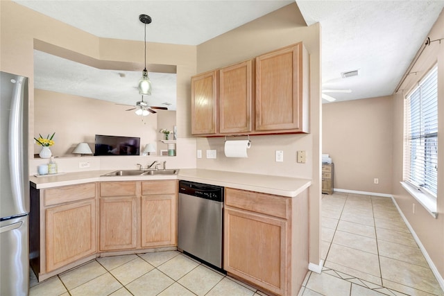 kitchen with light countertops, appliances with stainless steel finishes, light brown cabinets, a sink, and light tile patterned flooring