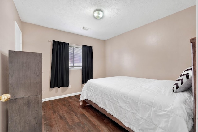 bedroom featuring a textured ceiling, wood finished floors, visible vents, and baseboards