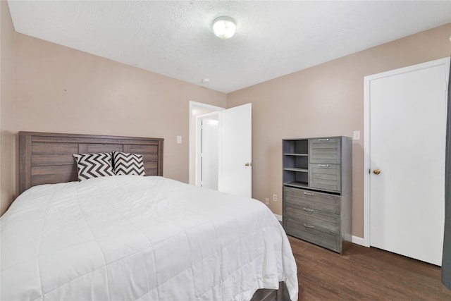 bedroom with a textured ceiling, dark wood-style flooring, and baseboards