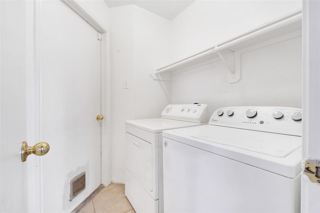 laundry room with laundry area, washing machine and clothes dryer, and light tile patterned floors