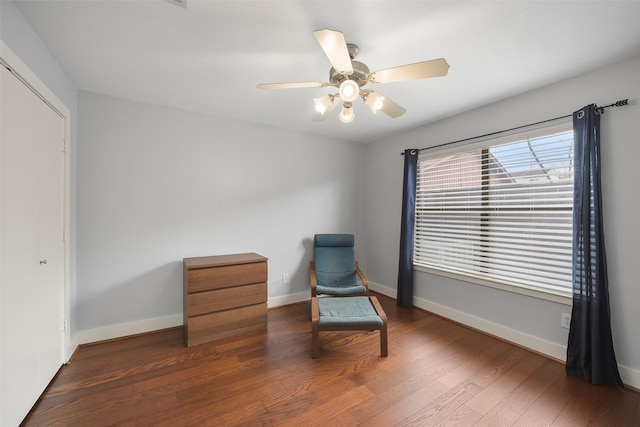 living area featuring a ceiling fan, baseboards, and wood finished floors