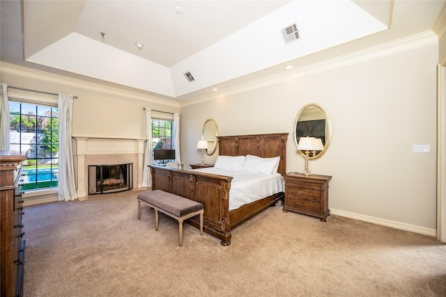 bedroom with a tray ceiling, light colored carpet, visible vents, ornamental molding, and a glass covered fireplace