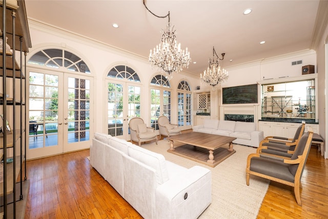 living room with french doors, light wood-style floors, visible vents, and an inviting chandelier