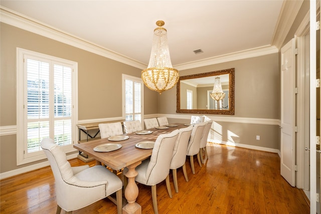 dining space featuring an inviting chandelier, crown molding, and wood finished floors