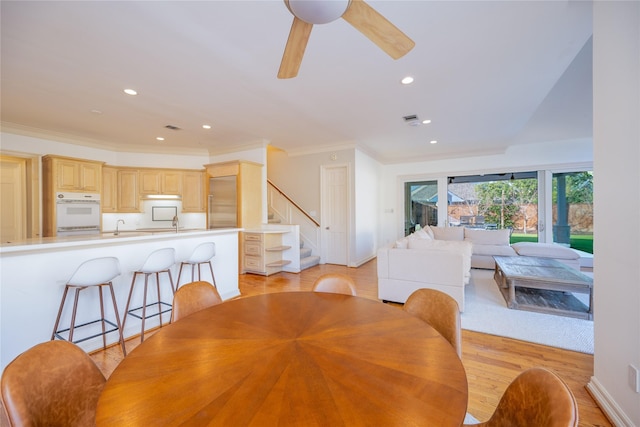 dining room featuring ornamental molding, a wood stove, light wood finished floors, and visible vents