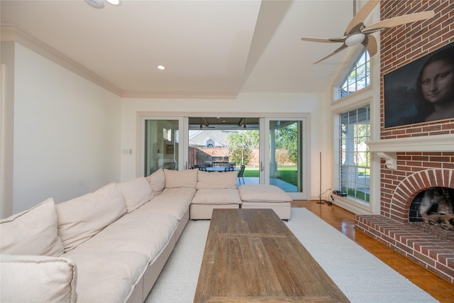 living area with recessed lighting, wood finished floors, a ceiling fan, a brick fireplace, and crown molding