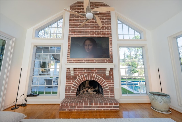 unfurnished living room featuring lofted ceiling, a brick fireplace, ceiling fan, and wood finished floors