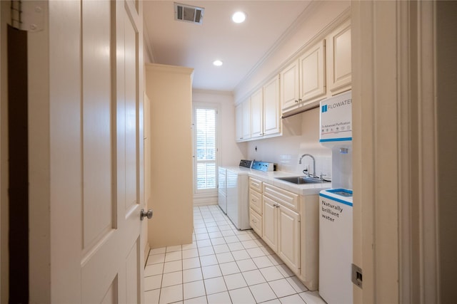 kitchen with crown molding, light countertops, visible vents, a sink, and independent washer and dryer