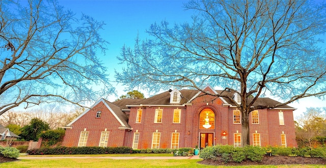 colonial home with a front lawn and brick siding