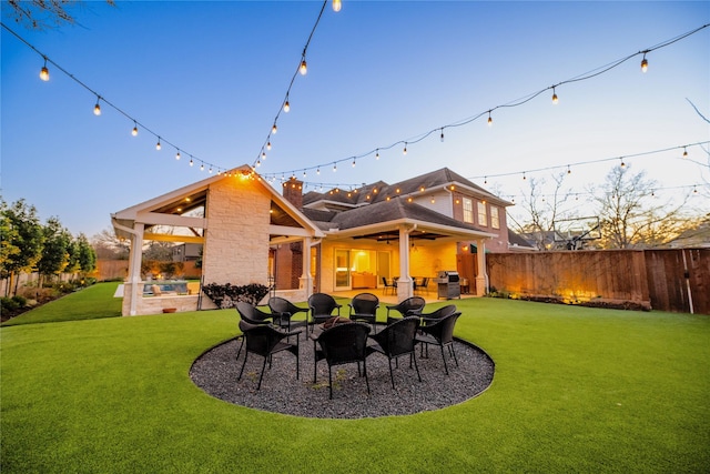 rear view of house featuring a fenced backyard, a chimney, ceiling fan, a yard, and a patio area