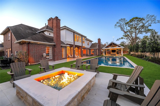 view of swimming pool featuring a fire pit, a yard, a patio area, and a fenced in pool