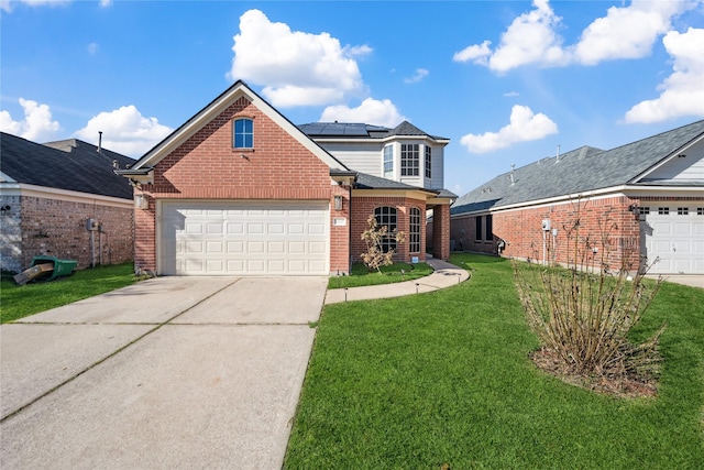 traditional home with brick siding, solar panels, an attached garage, a front yard, and driveway