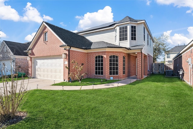 traditional-style house with central air condition unit, a front lawn, roof mounted solar panels, a garage, and brick siding