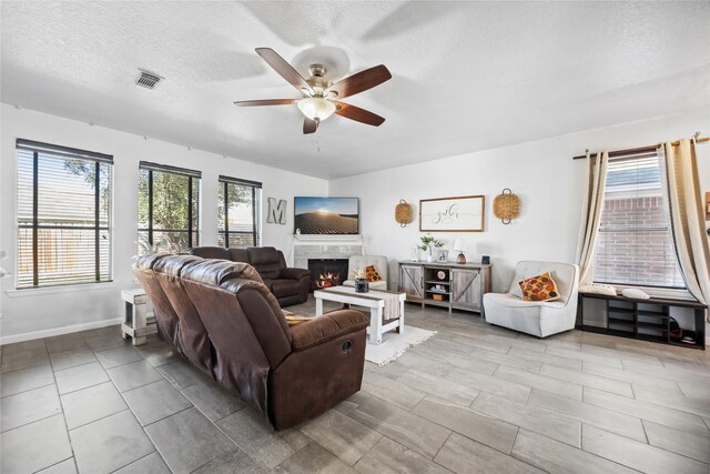 living room with visible vents, plenty of natural light, a textured ceiling, and a tile fireplace