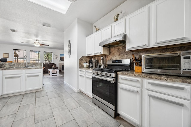 kitchen with visible vents, stainless steel range with gas stovetop, white cabinets, under cabinet range hood, and backsplash