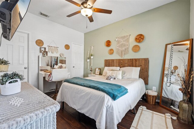 bedroom with wood finished floors, visible vents, and ceiling fan