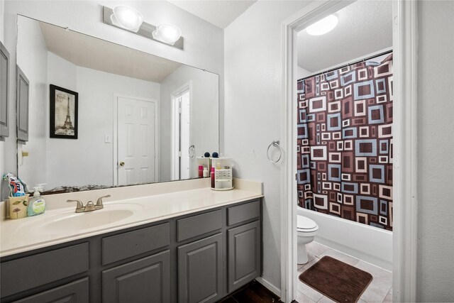 full bath with tile patterned floors, toilet, vanity, and shower / tub combo