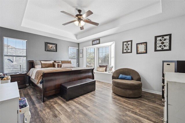 bedroom with baseboards, a raised ceiling, and dark wood-type flooring