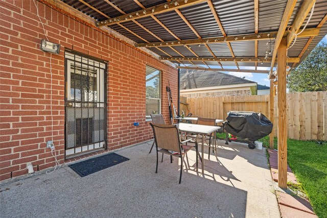 view of patio with area for grilling, outdoor dining space, and fence