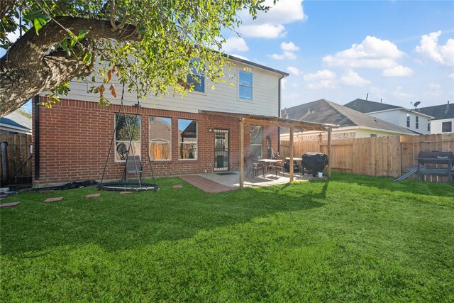 rear view of house with a lawn, a pergola, a patio, a fenced backyard, and brick siding