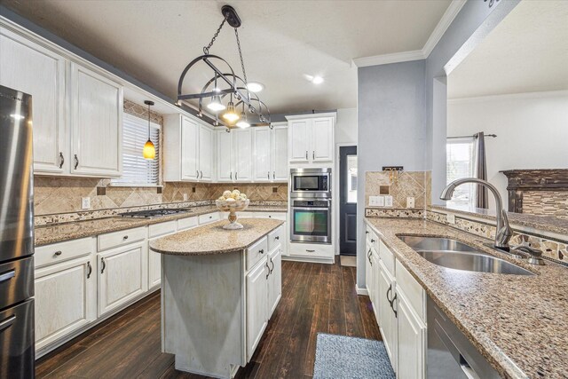 kitchen featuring light stone counters, dark wood-style flooring, crown molding, stainless steel appliances, and a sink