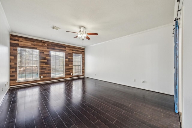 spare room with visible vents, ceiling fan, ornamental molding, wood finished floors, and wood walls