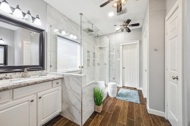 bathroom with wood finish floors, vanity, visible vents, and a stall shower