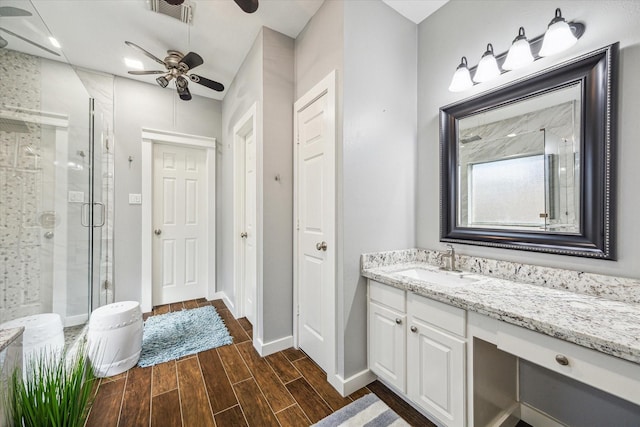 bathroom with visible vents, baseboards, vanity, a shower stall, and wood finish floors