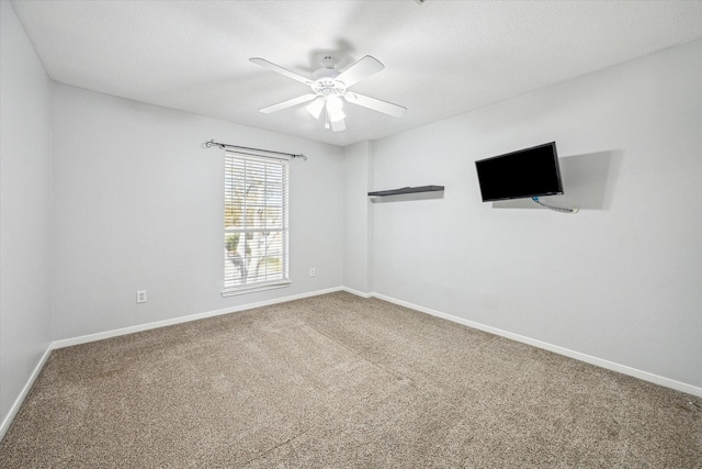 spare room featuring a ceiling fan, carpet, and baseboards