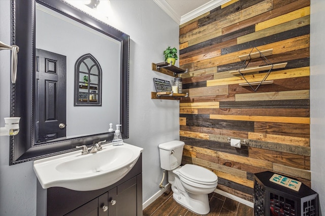 bathroom with toilet, wood walls, ornamental molding, and vanity