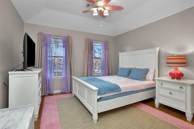 bedroom featuring a ceiling fan, a raised ceiling, wood finished floors, and visible vents